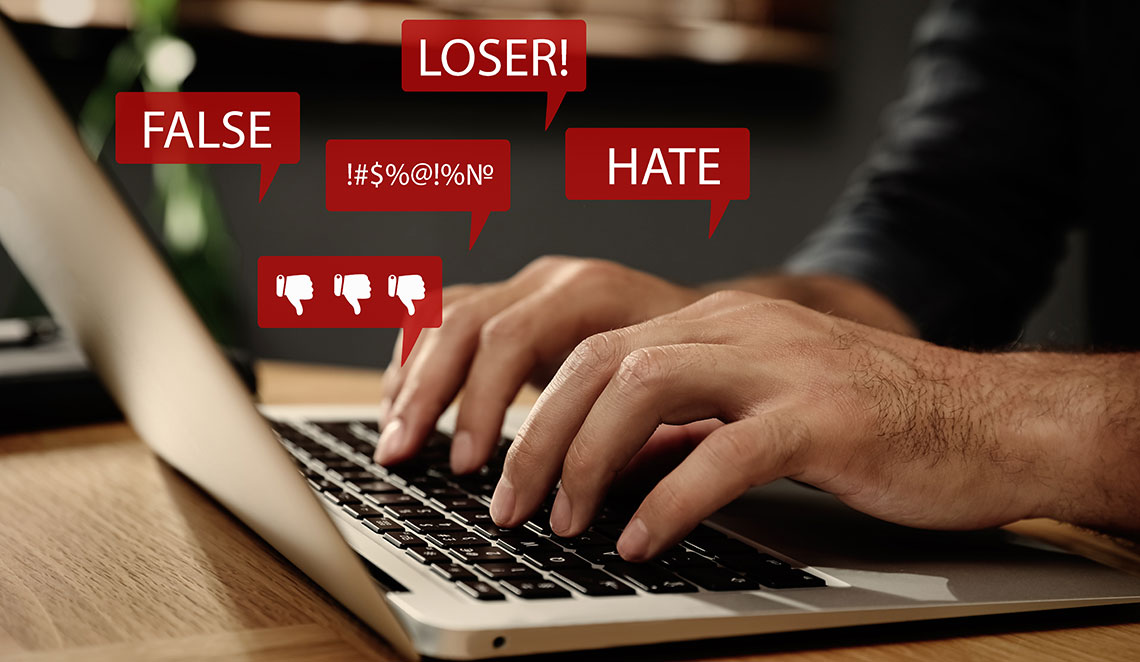 Foto einer Person am Laptop in Nahaufnahme und beispielhafte Einblendung eingehemder Nachrichten wie Loser, Hate, False etc.