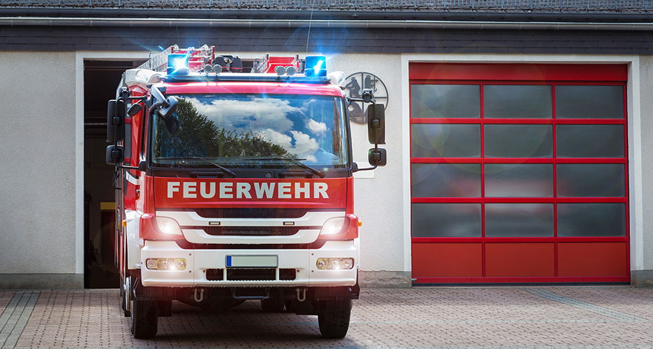 Teaserbild Feuerwehrinfrastruktur-Richtlinie Teaserbild mit einem Foto eines Feuerwehrfahrzeuges vor einer Feuerwache